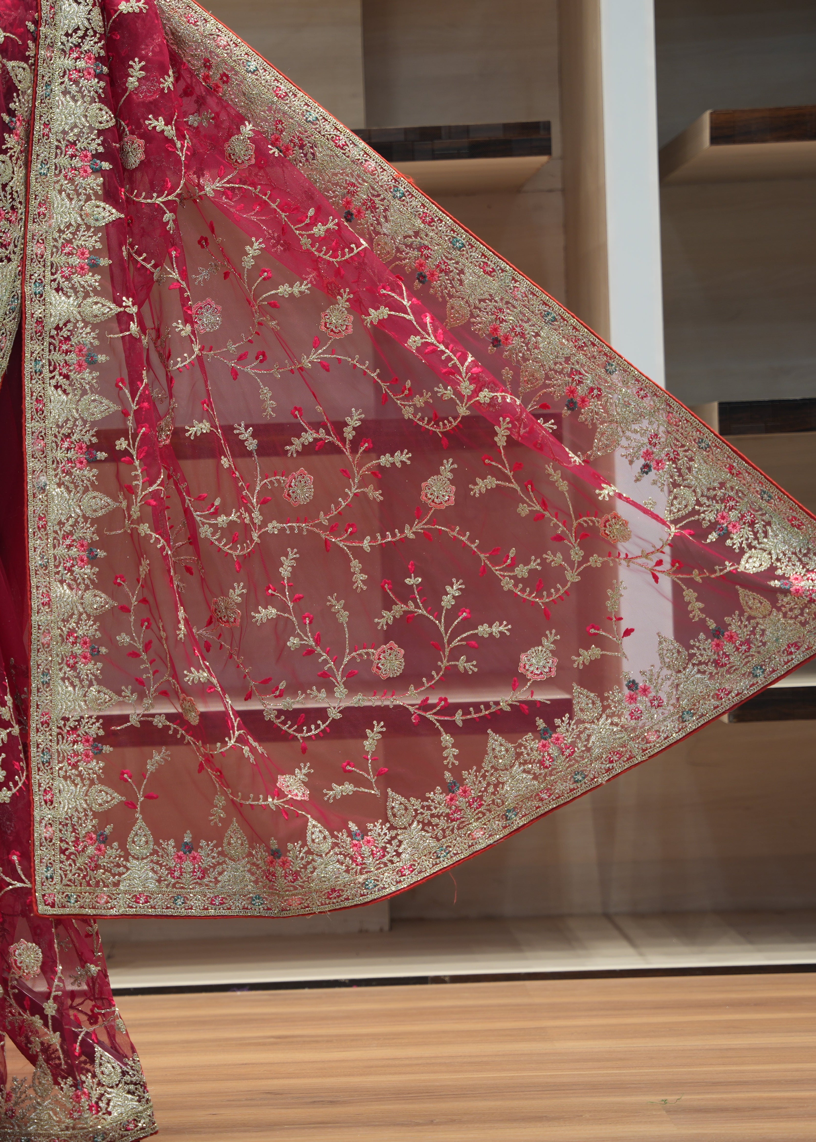 Red saree with gold embroidery on a wooden floor