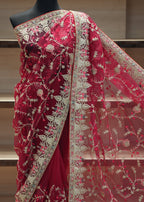 Red saree with intricate white embroidery on a mannequin against a neutral background