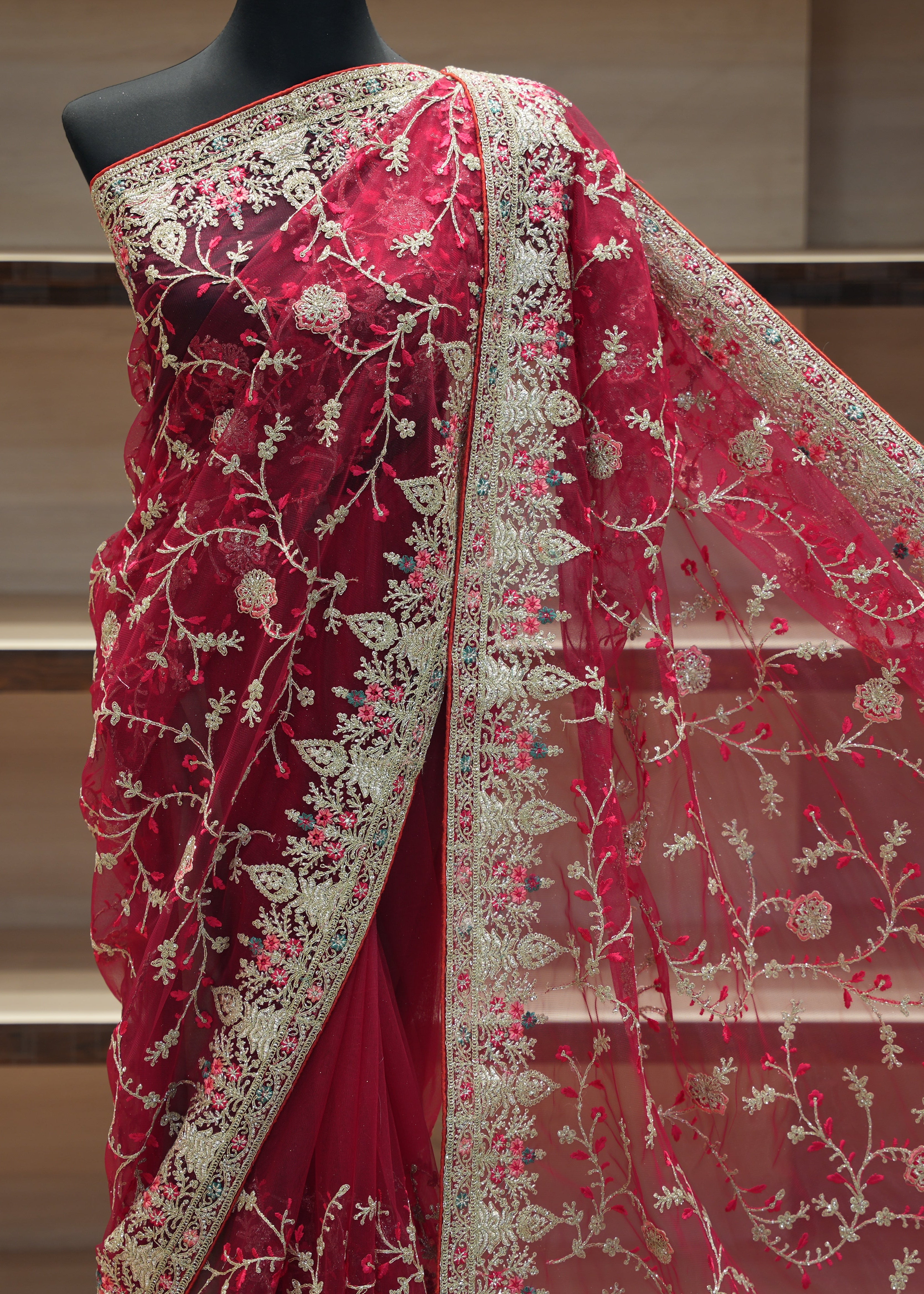 Red saree with intricate white embroidery on a mannequin against a neutral background