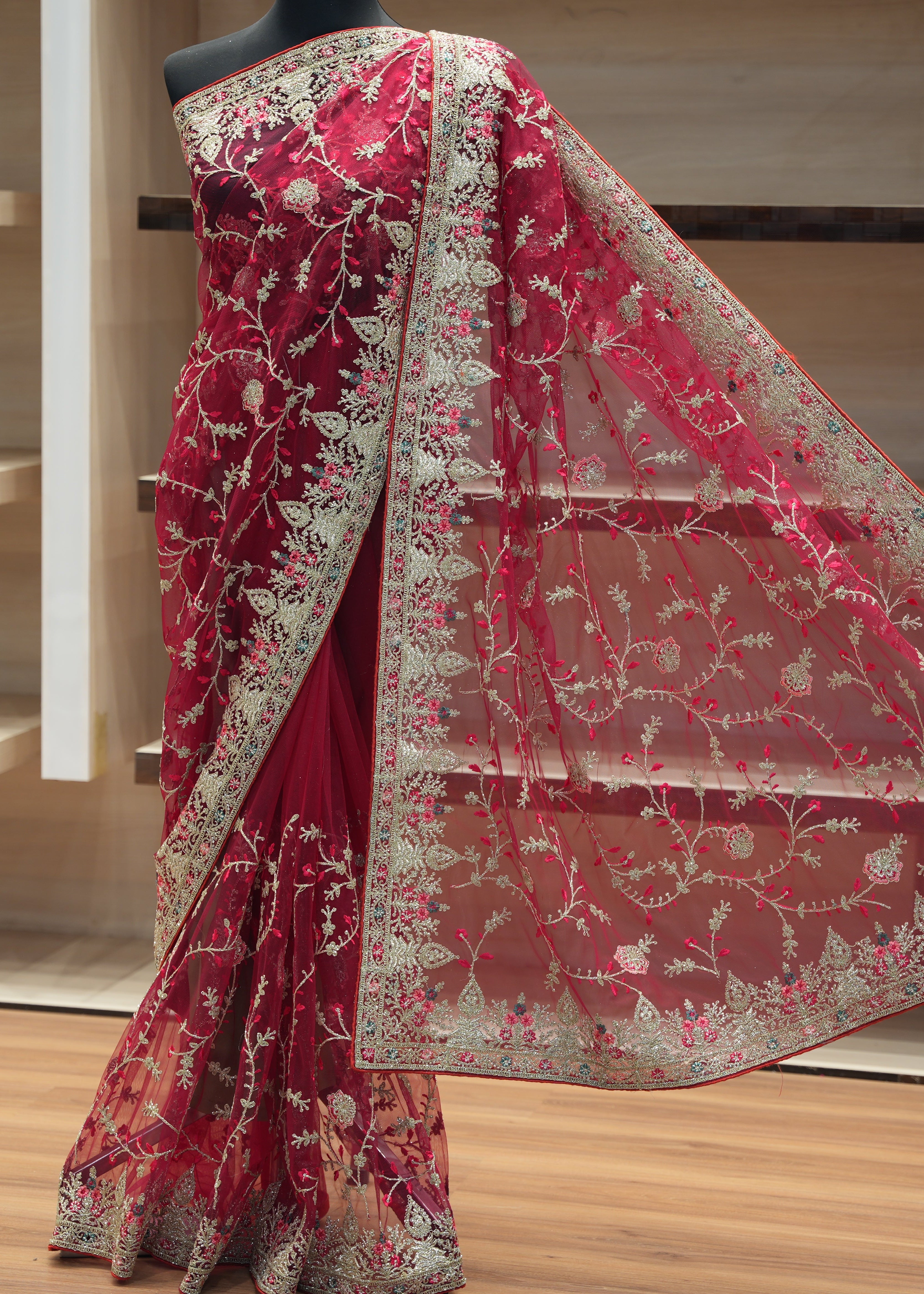 Red saree with floral patterns on a wooden floor
