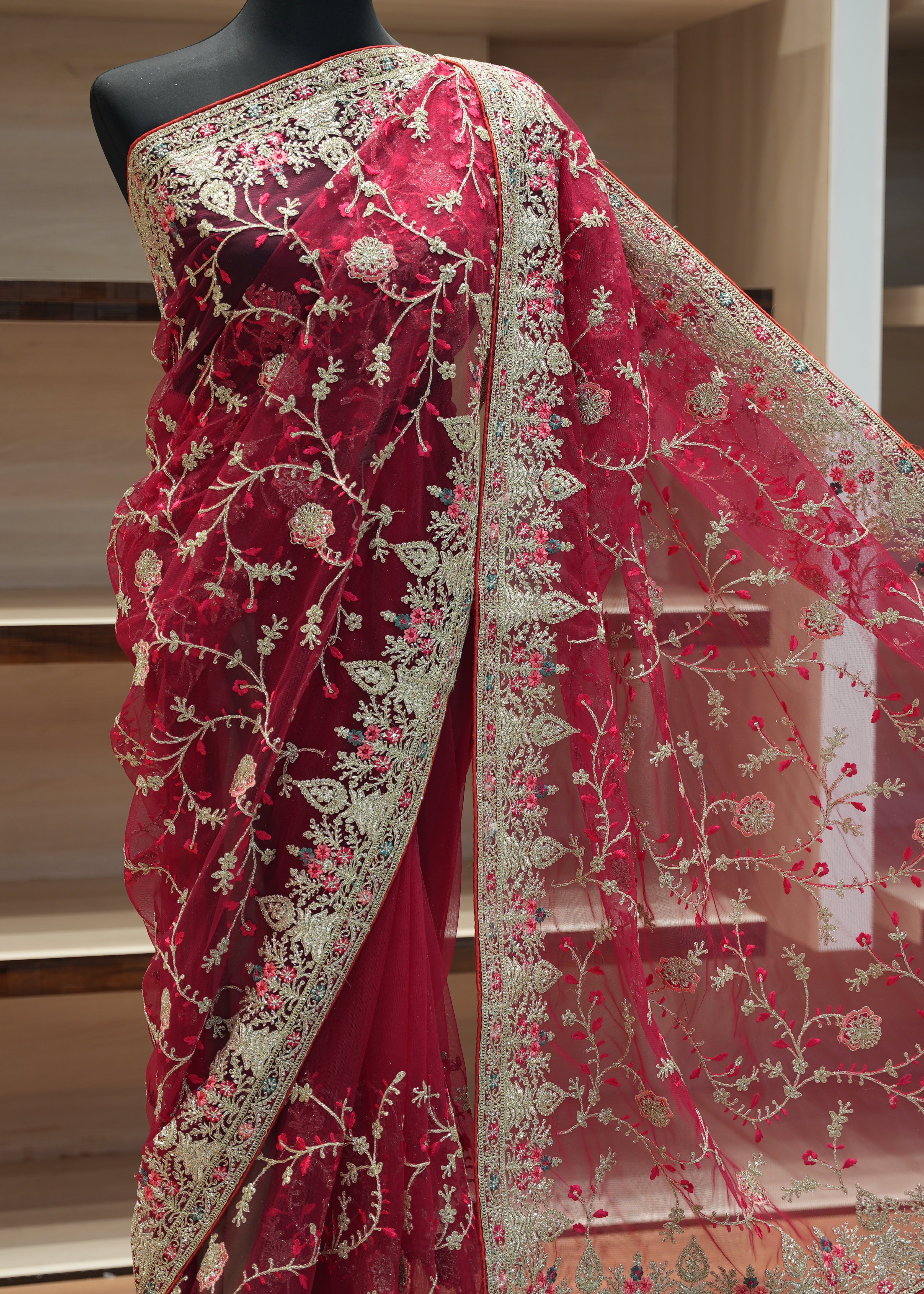 Red saree with intricate white embroidery on a mannequin against a neutral background