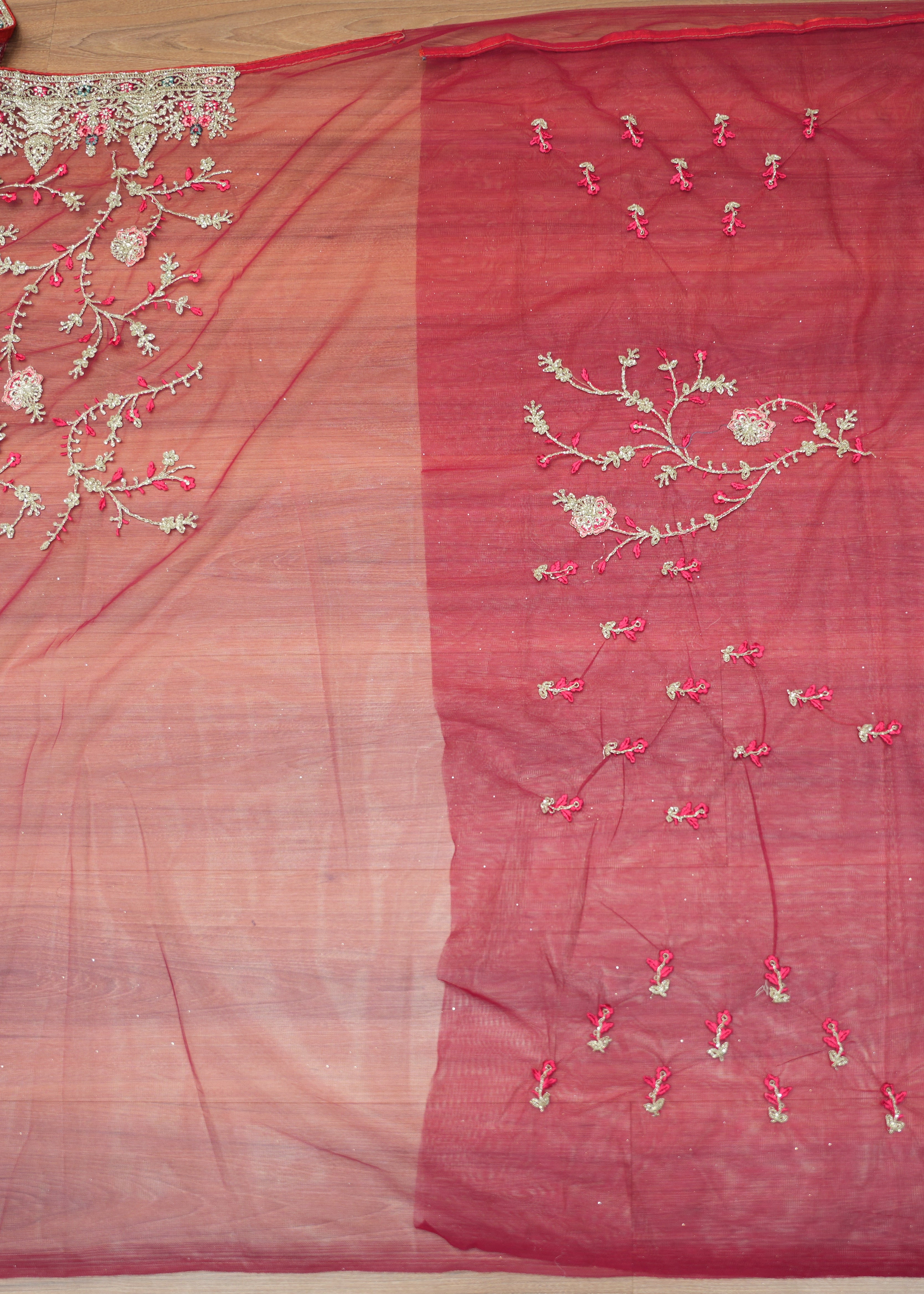 Red fabric with floral embroidery on a wooden surface