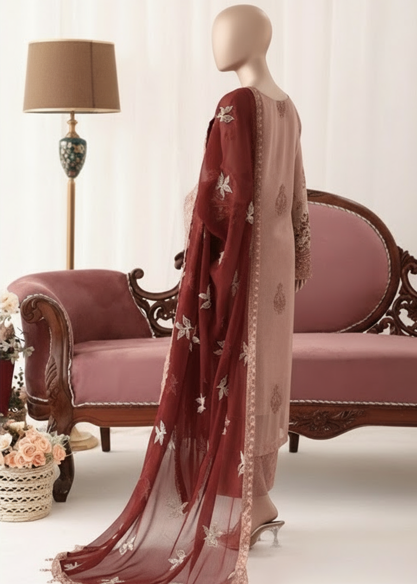 Woman in traditional outfit with embroidered pink and red dress and dupatta, sitting on a decorative sofa.