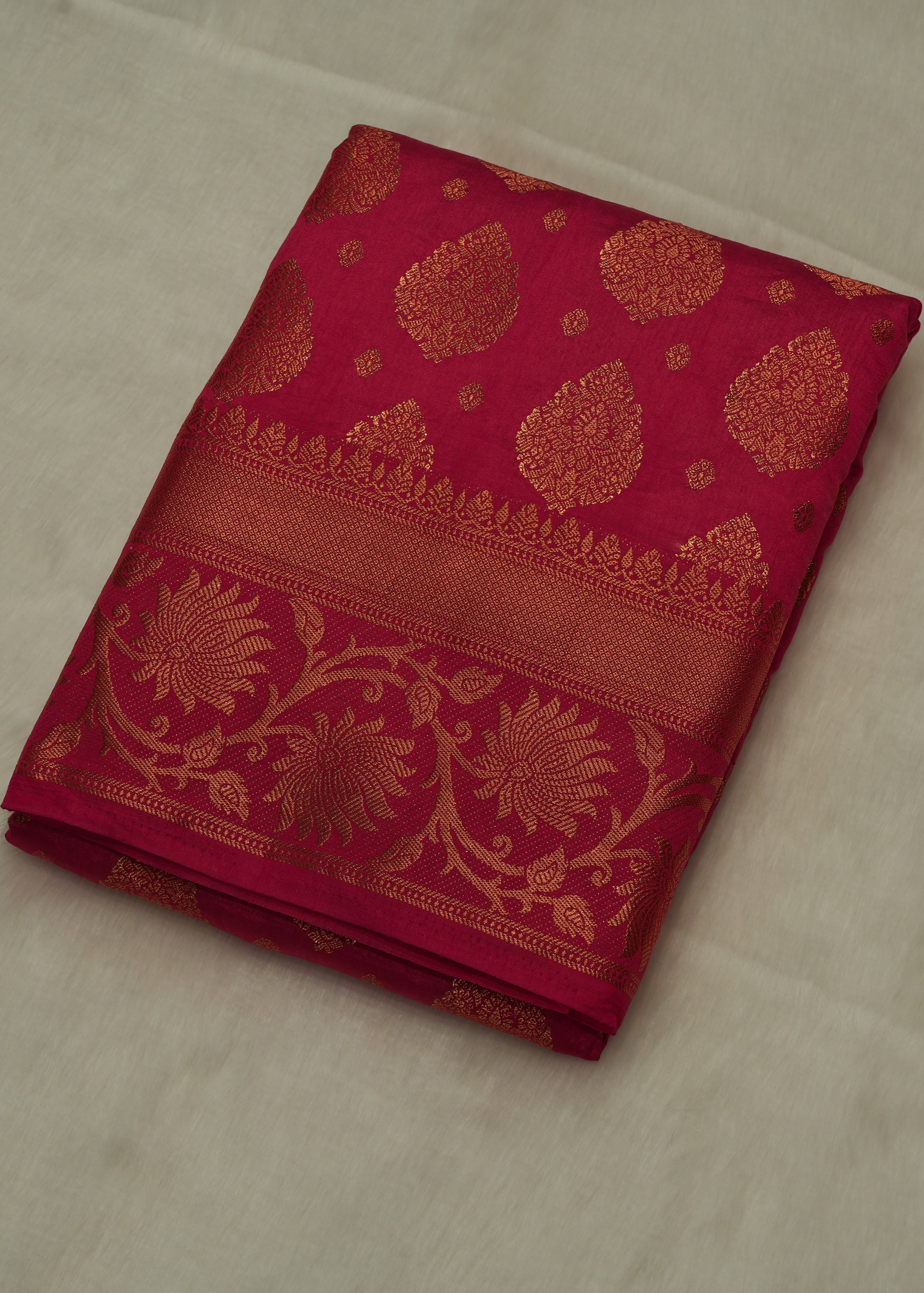 Folded red fabric with gold patterns on a beige surface