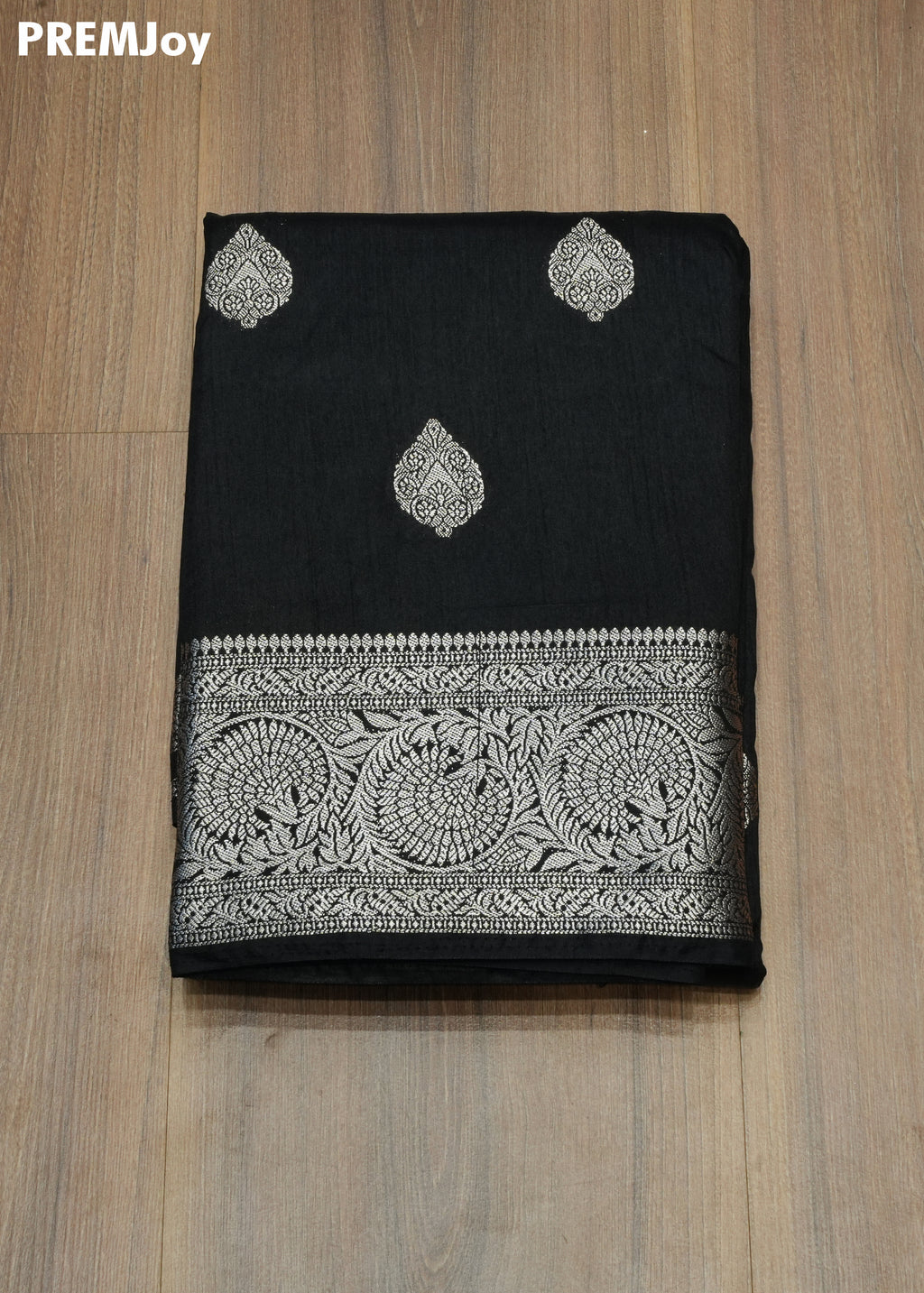 Black saree with white embroidery on a wooden surface, PREMJoy brand visible