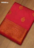 Red saree with gold embroidery on a wooden surface, branded 'PREMJoy'.