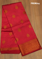 Red saree with gold patterns on a wooden surface, branded 'PREMJoy'.