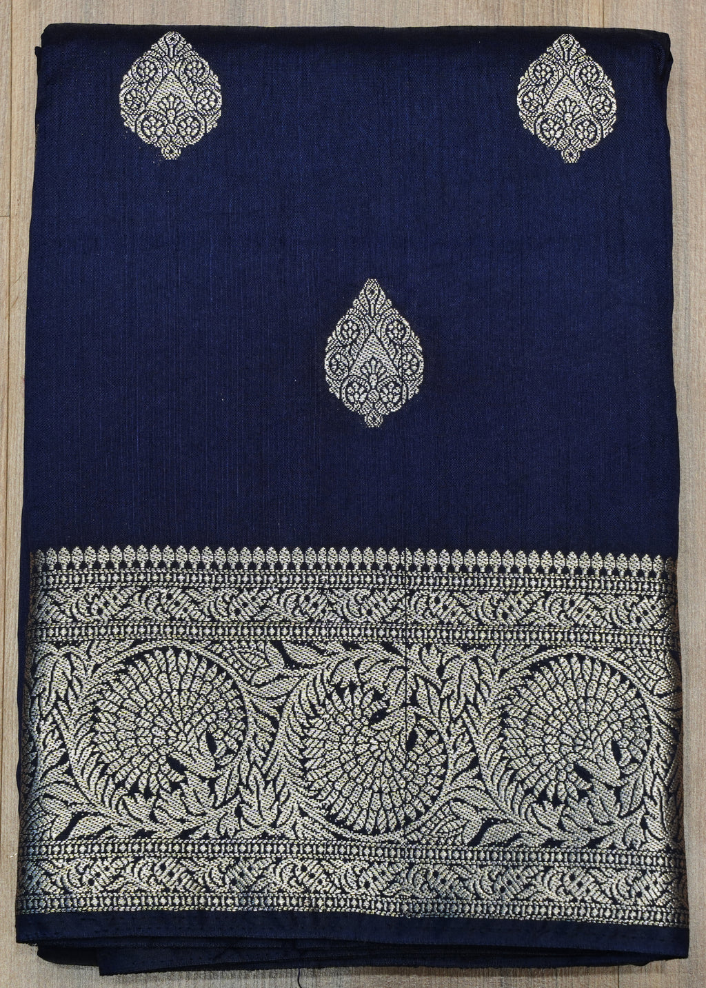 Navy blue fabric with silver embroidery on a wooden surface