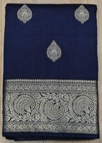 Navy blue fabric with silver embroidery on a wooden surface