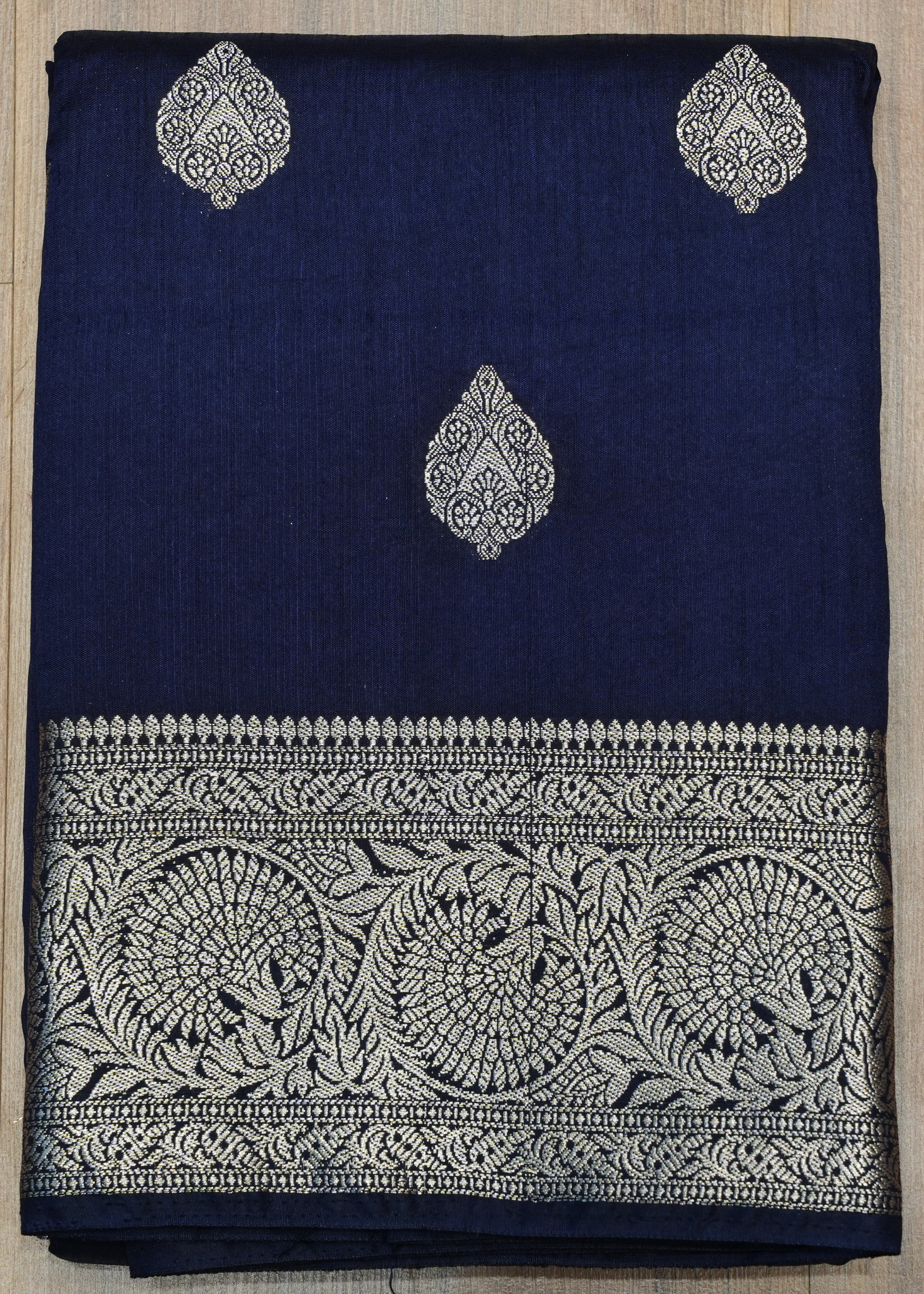 Navy blue fabric with silver embroidery on a wooden surface