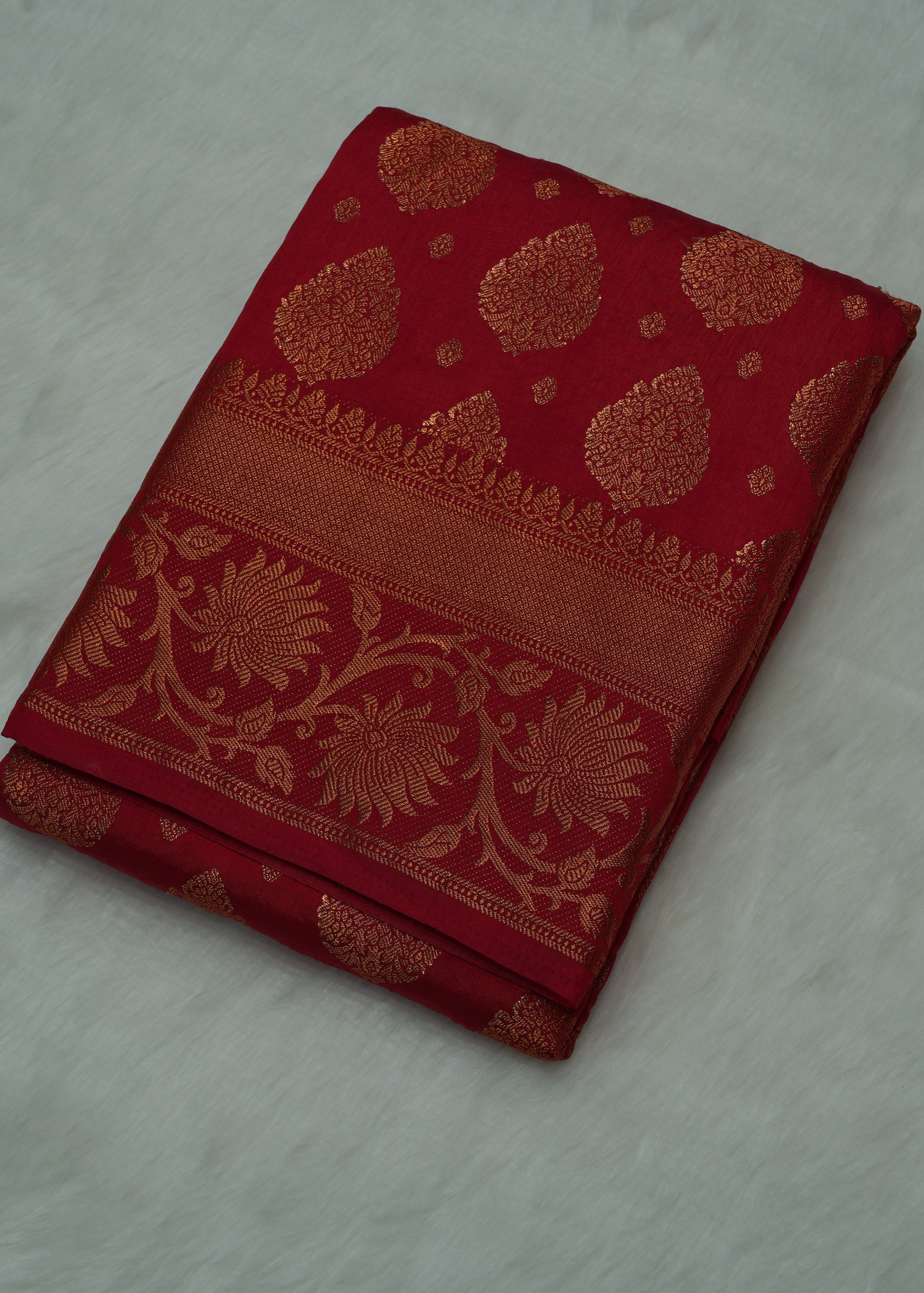 Folded red fabric with gold patterns on a light gray background