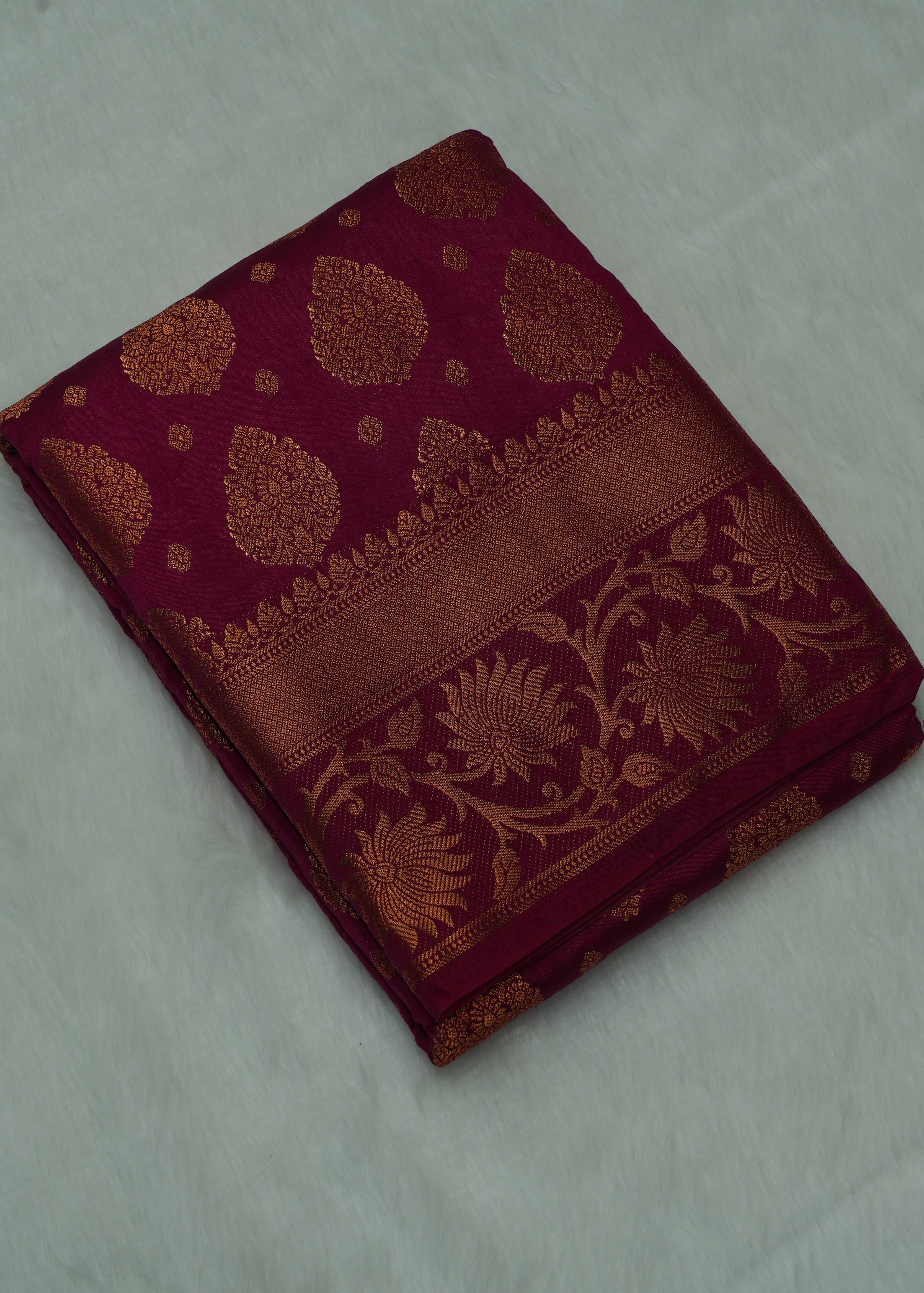 Maroon fabric with gold floral patterns on a white background