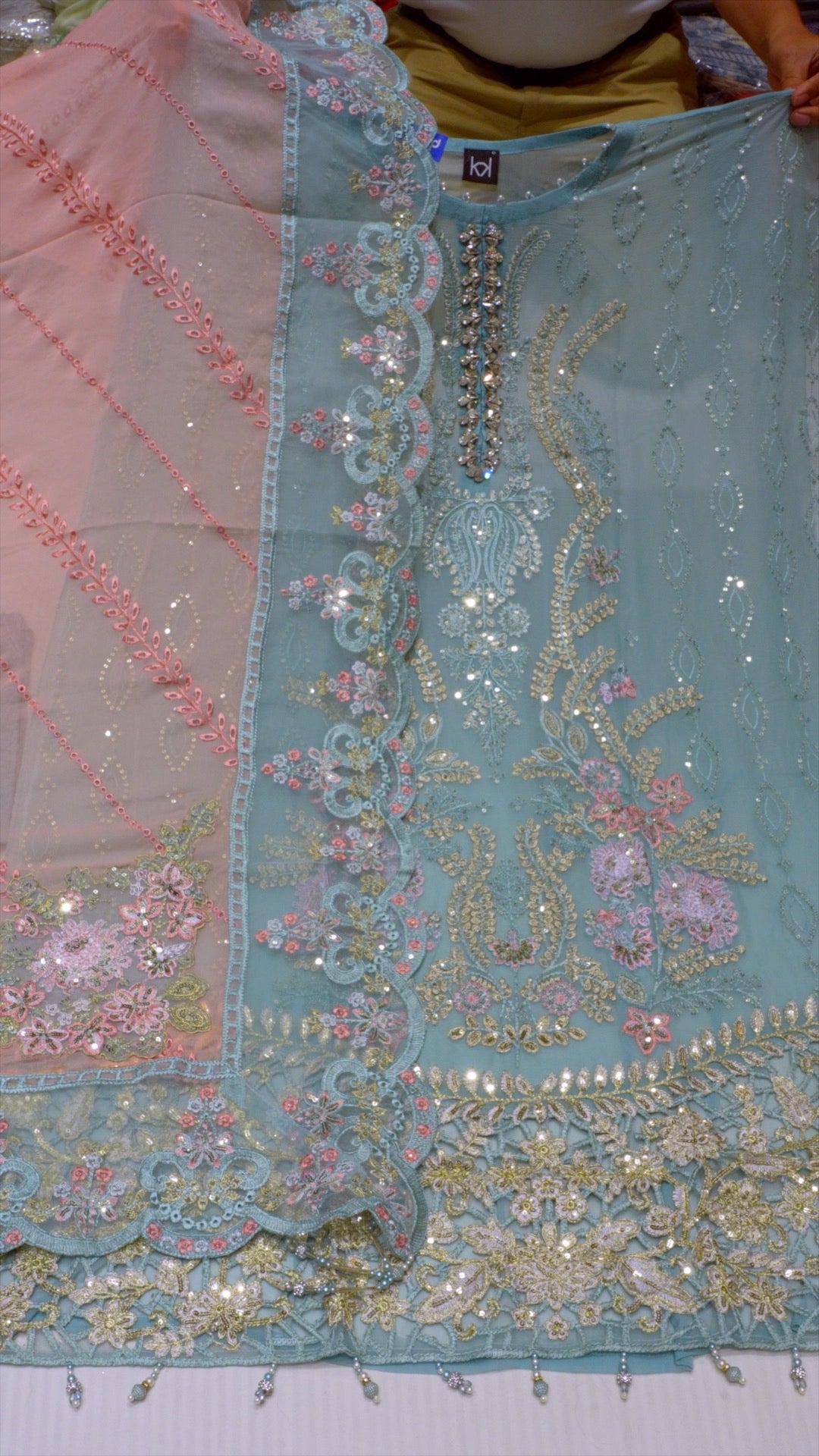 Close-up of a piece of fabric with intricate embroidery and embellishments.