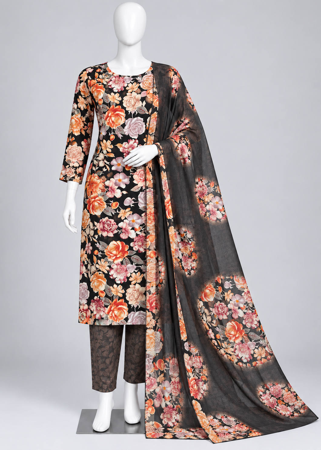 A three-piece women's salwar kameez suit set displayed on a white mannequin. The set features a black kurta with a vibrant multicolor floral print, matching printed trousers, and a sheer black dupatta with a large floral motif.